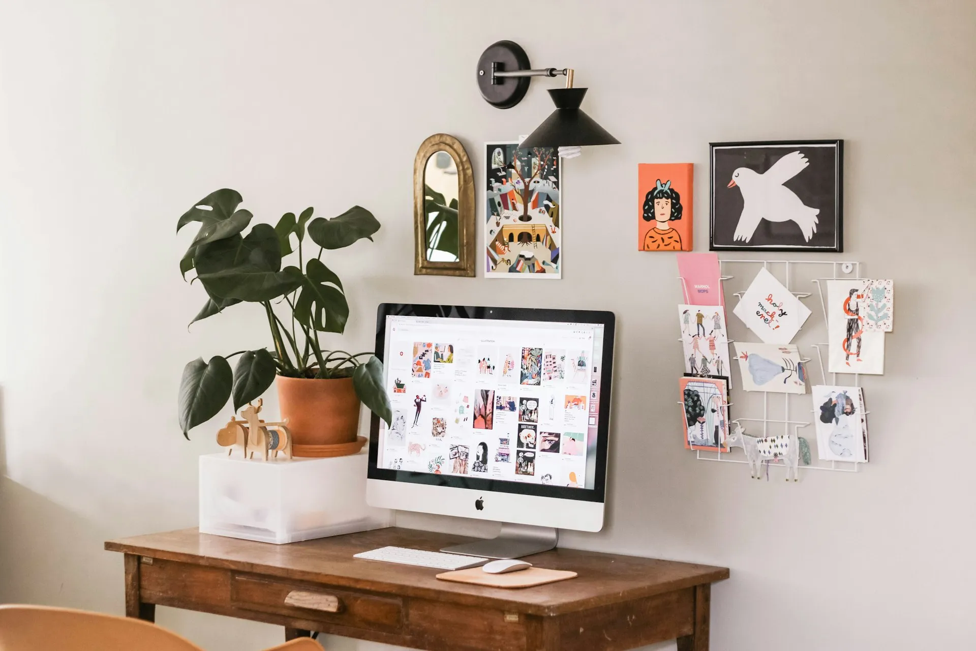 Schreibtisch mit iMac, Pflanze und Bildern an der Wand