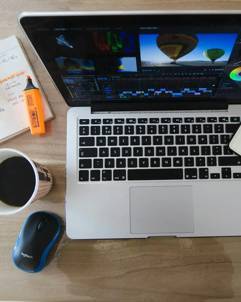 Laptop mit Bildbearbeitung, Notizbuch und Kaffee