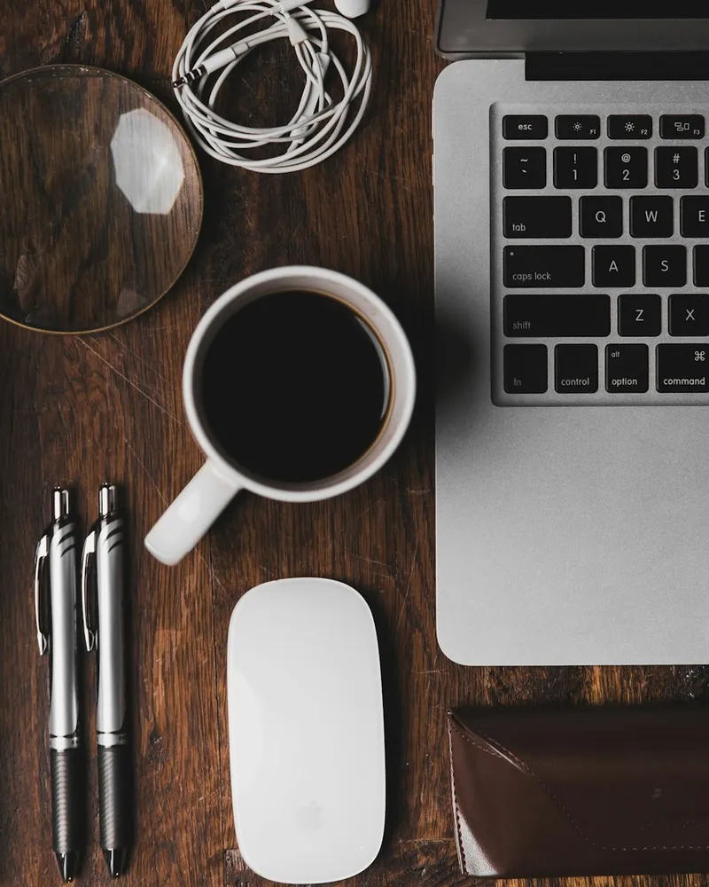 Schreibtisch von oben mit Kaffee, Stiften und Laptop